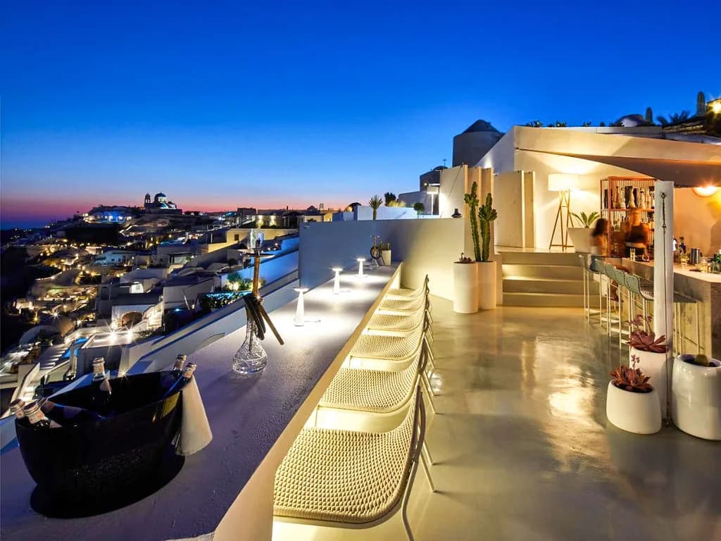 The lit bar counter running the length of the rooftop as the sky turns deep blue.