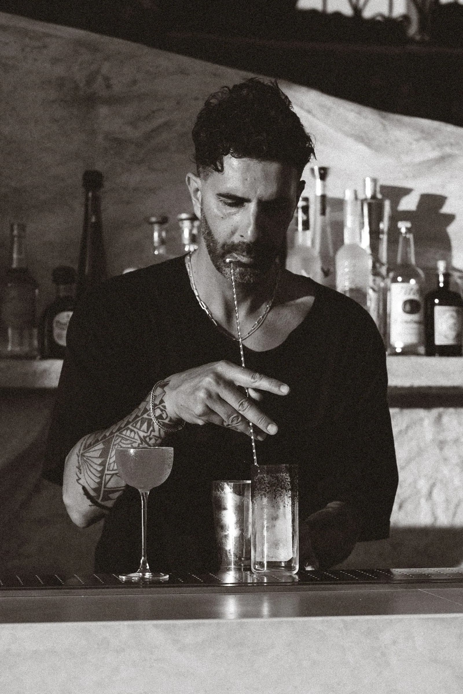 A bartender stirring a cocktail down, in black and white.