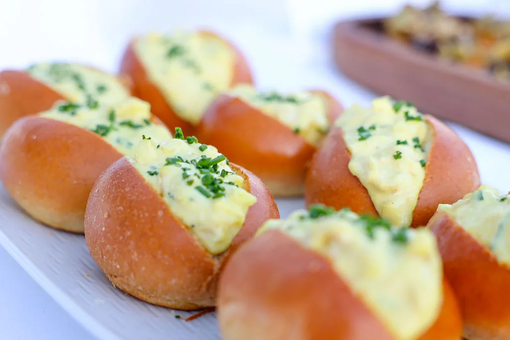 Brioche rolls filled and finished with chives, close on the service tray.